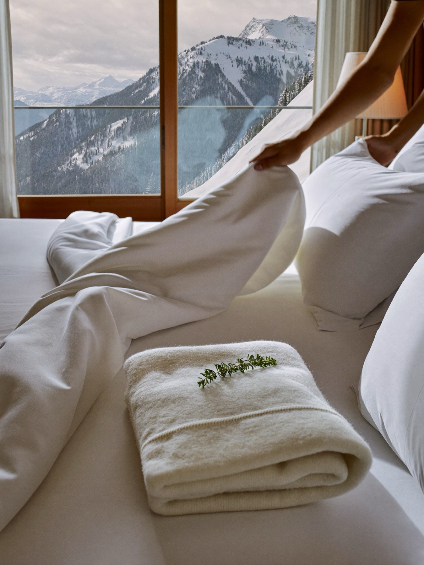 Crisp white linens being finished in a bright alpine bedroom
